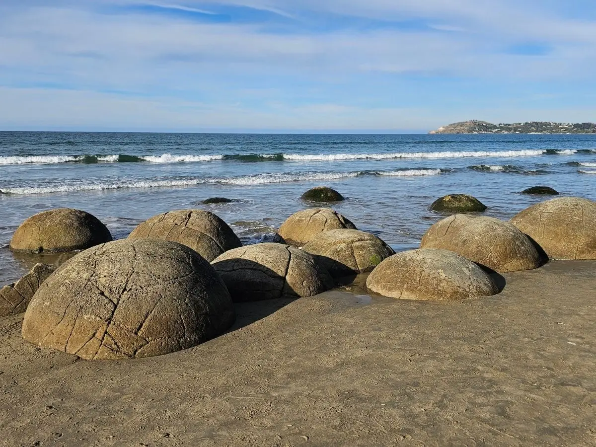 Moeraki Boulders scattered on Koekohe Beach, North Otago, with Oamaru headland in the distance